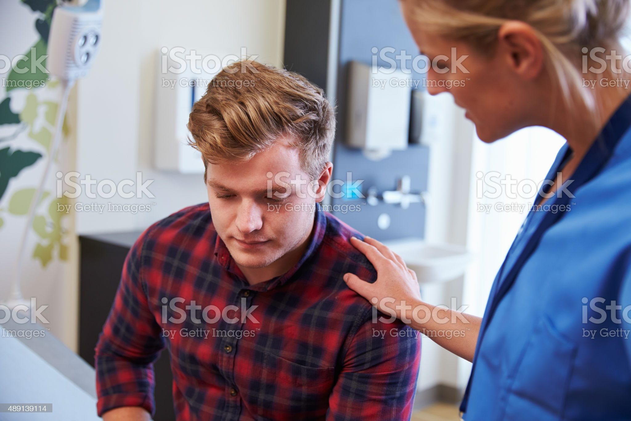 Male Patient Being Reassured By Nurse In Hospital Room